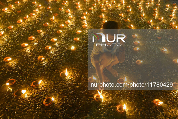 A child lights oil lamps at the riverside of the Ganges in Kolkata, India, on November 15, 2024, during the Dev Deepavali celebration in the...