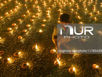 A child lights oil lamps at the riverside of the Ganges in Kolkata, India, on November 15, 2024, during the Dev Deepavali celebration in the...