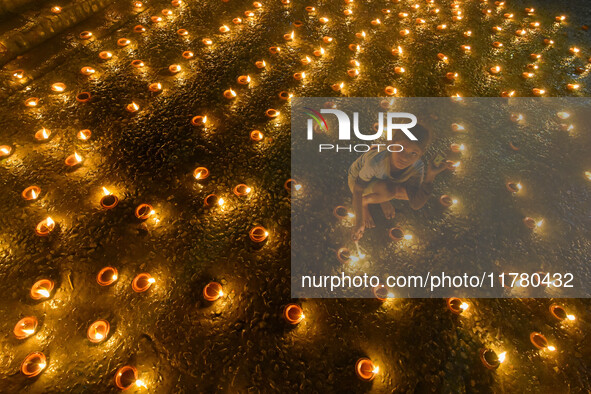 A child lights oil lamps at the riverside of the Ganges in Kolkata, India, on November 15, 2024, during the Dev Deepavali celebration in the...