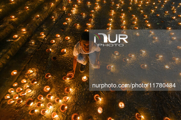 A child lights oil lamps at the riverside of the Ganges in Kolkata, India, on November 15, 2024, during the Dev Deepavali celebration in the...