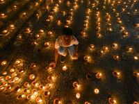 A child lights oil lamps at the riverside of the Ganges in Kolkata, India, on November 15, 2024, during the Dev Deepavali celebration in the...