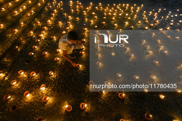 A child lights oil lamps at the riverside of the Ganges in Kolkata, India, on November 15, 2024, during the Dev Deepavali celebration in the...