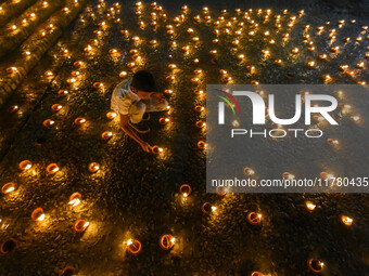 A child lights oil lamps at the riverside of the Ganges in Kolkata, India, on November 15, 2024, during the Dev Deepavali celebration in the...