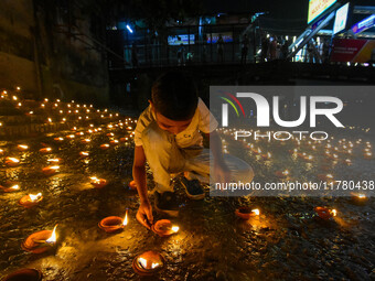 A child lights oil lamps at the riverside of the Ganges in Kolkata, India, on November 15, 2024, during the Dev Deepavali celebration in the...