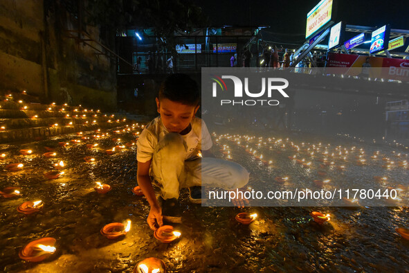 A child lights oil lamps at the riverside of the Ganges in Kolkata, India, on November 15, 2024, during the Dev Deepavali celebration in the...