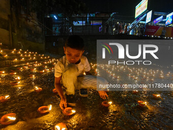 A child lights oil lamps at the riverside of the Ganges in Kolkata, India, on November 15, 2024, during the Dev Deepavali celebration in the...