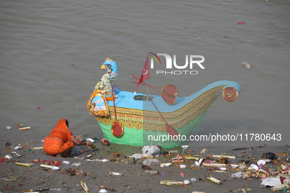 A woman collects items thrown by devotees as religious offerings after the celebrations of the 'Boita Bandana,' also known as 'Danga Bhasa,'...