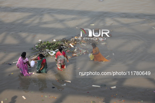 Women collect holy water next to items thrown by devotees as religious offerings after the celebrations of the 'Boita Bandana,' also known a...