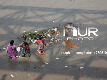 Women collect holy water next to items thrown by devotees as religious offerings after the celebrations of the 'Boita Bandana,' also known a...