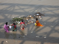 Women collect holy water next to items thrown by devotees as religious offerings after the celebrations of the 'Boita Bandana,' also known a...