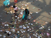 A woman collects items thrown by devotees as religious offerings after the celebrations of the 'Boita Bandana,' also known as 'Danga Bhasa,'...