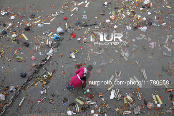 A woman collects items thrown by devotees as religious offerings after the celebrations of the 'Boita Bandana,' also known as 'Danga Bhasa,'...