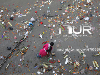 A woman collects items thrown by devotees as religious offerings after the celebrations of the 'Boita Bandana,' also known as 'Danga Bhasa,'...