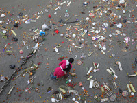 A woman collects items thrown by devotees as religious offerings after the celebrations of the 'Boita Bandana,' also known as 'Danga Bhasa,'...