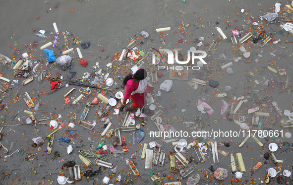 A woman collects items thrown by devotees as religious offerings after the celebrations of the 'Boita Bandana,' also known as 'Danga Bhasa,'...