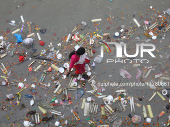 A woman collects items thrown by devotees as religious offerings after the celebrations of the 'Boita Bandana,' also known as 'Danga Bhasa,'...