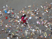 A woman collects items thrown by devotees as religious offerings after the celebrations of the 'Boita Bandana,' also known as 'Danga Bhasa,'...