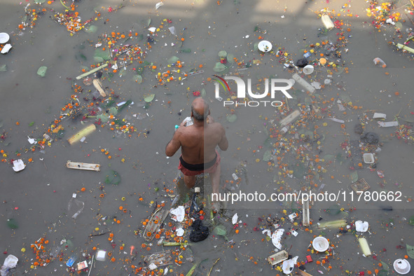 A man offers prayer among the items thrown by devotees as religious offerings after the celebrations of the 'Boita Bandana,' also known as '...