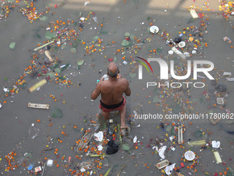 A man offers prayer among the items thrown by devotees as religious offerings after the celebrations of the 'Boita Bandana,' also known as '...