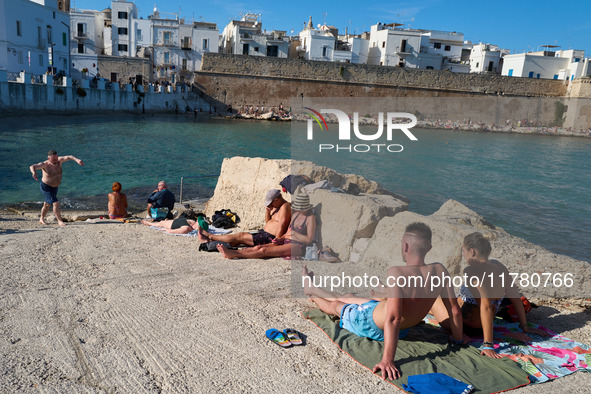 Swimmers relax in the warm Mediterranean waters on a sunny Sunday afternoon in Monopoli, Italy, on October 27, 2024. This image shows the co...