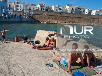 Swimmers relax in the warm Mediterranean waters on a sunny Sunday afternoon in Monopoli, Italy, on October 27, 2024. This image shows the co...