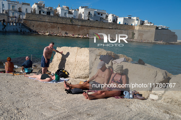 Swimmers relax in the warm Mediterranean waters on a sunny Sunday afternoon in Monopoli, Italy, on October 27, 2024. This image shows the co...