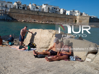 Swimmers relax in the warm Mediterranean waters on a sunny Sunday afternoon in Monopoli, Italy, on October 27, 2024. This image shows the co...