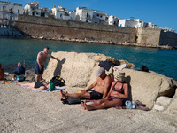 Swimmers relax in the warm Mediterranean waters on a sunny Sunday afternoon in Monopoli, Italy, on October 27, 2024. This image shows the co...