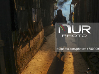 A man walks through the smoke at a slum in Dhaka, Bangladesh. A worker sprays pesticide to kill mosquitoes. The country records 1,705 dengue...