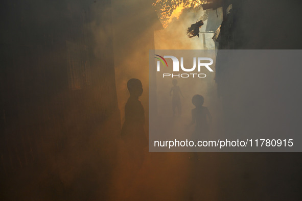 Children play in the smoke at a slum in the capital city of Dhaka, Bangladesh, as a worker sprays pesticide to kill mosquitoes. The country...