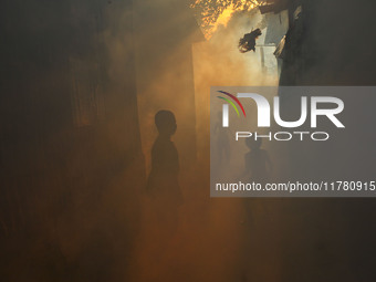 Children play in the smoke at a slum in the capital city of Dhaka, Bangladesh, as a worker sprays pesticide to kill mosquitoes. The country...