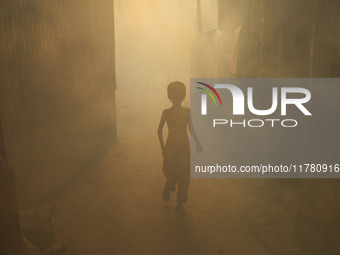 A child walks through the smoke at a slum in Dhaka, Bangladesh, as a worker sprays pesticide to kill mosquitoes. The country records 1,705 d...