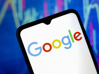 The Google logo appears on a smartphone screen, and in the background, a stock market graph is visible on the computer screen, in Reno, Unit...