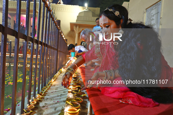 A woman lights earthen lamps at the Shrine Galtaji temple holy pond 'kund' as part of the Deep Mahotsav celebration on the eve of Dev Deepaw...