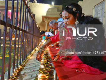 A woman lights earthen lamps at the Shrine Galtaji temple holy pond 'kund' as part of the Deep Mahotsav celebration on the eve of Dev Deepaw...