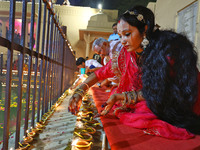 A woman lights earthen lamps at the Shrine Galtaji temple holy pond 'kund' as part of the Deep Mahotsav celebration on the eve of Dev Deepaw...