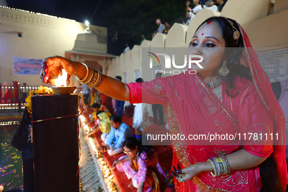 A woman lights earthen lamps at the Shrine Galtaji temple holy pond 'kund' as part of the Deep Mahotsav celebration on the eve of Dev Deepaw...