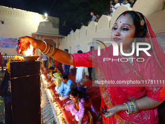 A woman lights earthen lamps at the Shrine Galtaji temple holy pond 'kund' as part of the Deep Mahotsav celebration on the eve of Dev Deepaw...