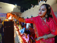 A woman lights earthen lamps at the Shrine Galtaji temple holy pond 'kund' as part of the Deep Mahotsav celebration on the eve of Dev Deepaw...