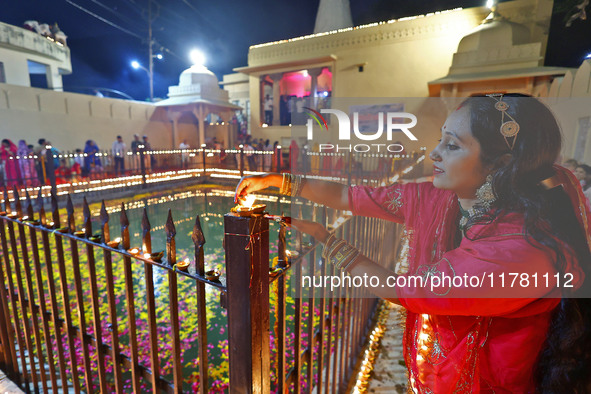 A woman lights earthen lamps at the Shrine Galtaji temple holy pond 'kund' as part of the Deep Mahotsav celebration on the eve of Dev Deepaw...