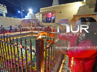 A woman lights earthen lamps at the Shrine Galtaji temple holy pond 'kund' as part of the Deep Mahotsav celebration on the eve of Dev Deepaw...