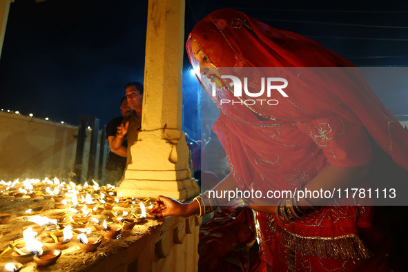 A woman lights earthen lamps at the Shrine Galtaji temple holy pond 'kund' as part of the Deep Mahotsav celebration on the eve of Dev Deepaw...