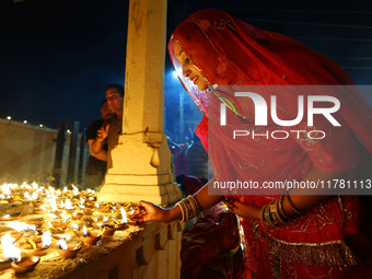 A woman lights earthen lamps at the Shrine Galtaji temple holy pond 'kund' as part of the Deep Mahotsav celebration on the eve of Dev Deepaw...