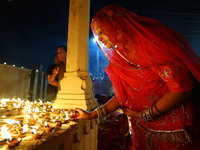 A woman lights earthen lamps at the Shrine Galtaji temple holy pond 'kund' as part of the Deep Mahotsav celebration on the eve of Dev Deepaw...