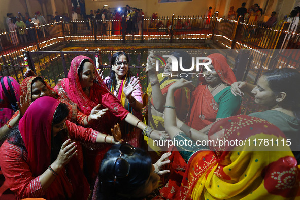 In Jaipur, Rajasthan, India, on November 15, 2024, people dance after lighting earthen lamps at the Shrine Galtaji temple holy pond 'kund' a...