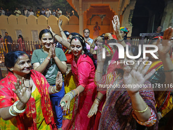 In Jaipur, Rajasthan, India, on November 15, 2024, people dance after lighting earthen lamps at the Shrine Galtaji temple holy pond 'kund' a...