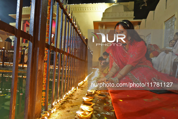 A woman lights earthen lamps at the Shrine Galtaji temple holy pond 'kund' as part of the Deep Mahotsav celebration on the eve of Dev Deepaw...