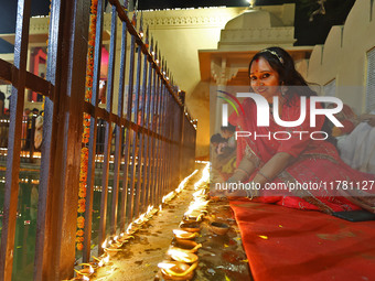 A woman lights earthen lamps at the Shrine Galtaji temple holy pond 'kund' as part of the Deep Mahotsav celebration on the eve of Dev Deepaw...