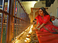 A woman lights earthen lamps at the Shrine Galtaji temple holy pond 'kund' as part of the Deep Mahotsav celebration on the eve of Dev Deepaw...