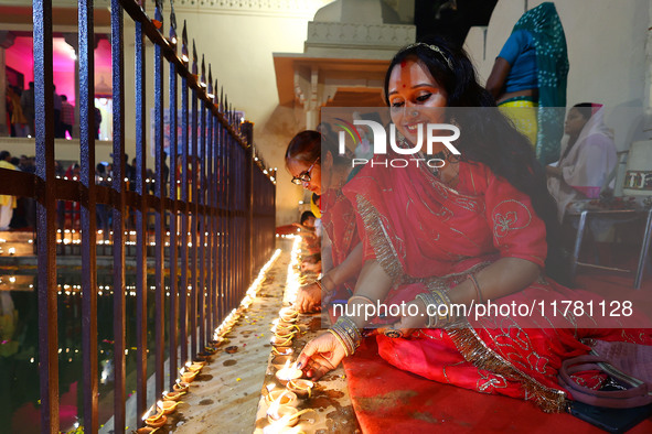 A woman lights earthen lamps at the Shrine Galtaji temple holy pond 'kund' as part of the Deep Mahotsav celebration on the eve of Dev Deepaw...